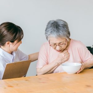 高齢者が食事でむせている